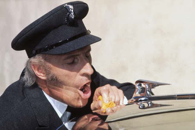 A man breathing on car's hood and wiping it