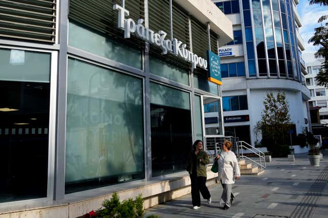 Women walk outside of a branch of &quot;Bank of Cyprus&quot; in central capital Nicosia, Cyprus, Wednesday, Jan. 24, 2024. Official figures show Cyprus making significant headway in weaning itself off Russian cash and business as it tries to clean up its image as a favorite destination for Moscow&#39;s money. According to the figures, the number of Russian clients using Cypriot banks has dropped 82% between 2014 up until the end of 2022. (AP Photo/Petros Karadjias)