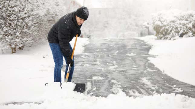 Un hombre paleando nieve durante una tormenta de nieve.