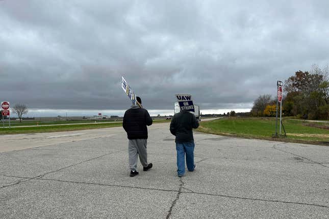 United Auto Workers members carry signs on a picket line outside a General Motors facility in Van Buren Township, Mich., on Monday, Oct. 30, 2023. (