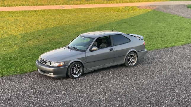 A Saab 9-3 Viggen sits in a driveway, next to a grass lawn