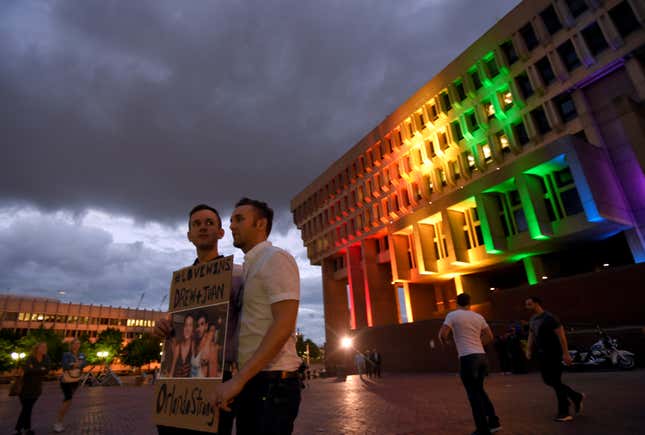 Stephen Flowers (L) and Nick Bazo, hold a photo of their friends Drew Leinonen and Juan Guerrero, both killed in the Orlando’s Pulse nightclub attack.