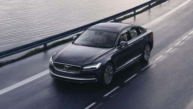 Une Volvo S90 noire circulant sur une route sinueuse près de l’eau