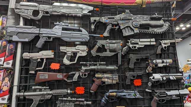Various video game guns are arranged on a wall.