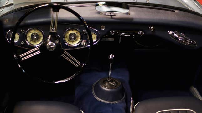 A photo of a vintage car interior including a steering wheel and gear stick. 