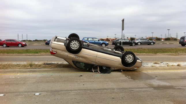 Car fallen upside-down on road in accident