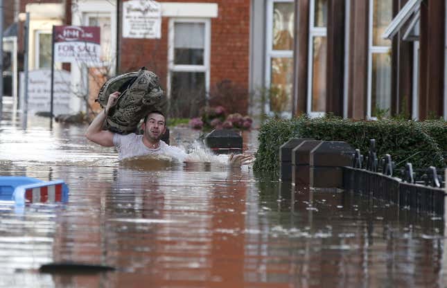A local resident carries a bag as he wades through flood water on a residential street in Carlisle, Britain December 6, 2015. British police have declared a major incident in northern England after prolonged heavy rain caused widespread flooding and forced emergency services to evacuate residents from their homes. REUTERS/Phil Noble