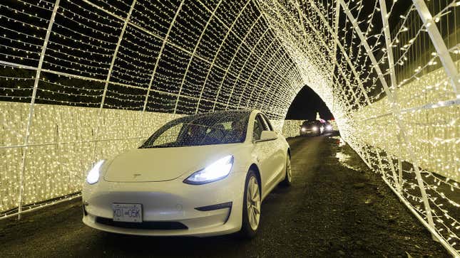 A photo of a Tesla car driving through fairy lights. 