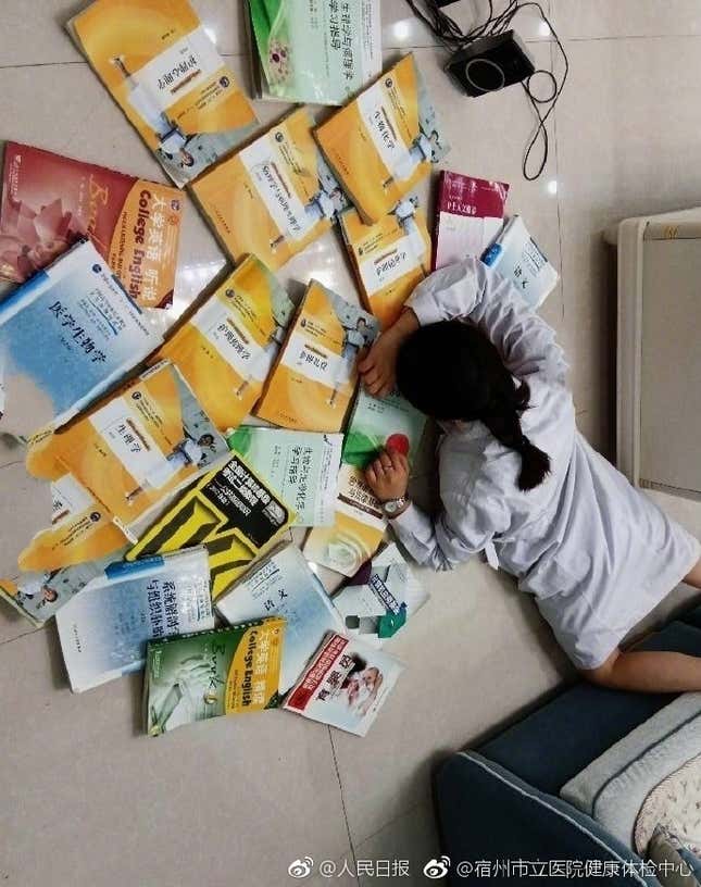 A student laying on the ground with books around her as a way to participate in the flaunt wealth challenge.