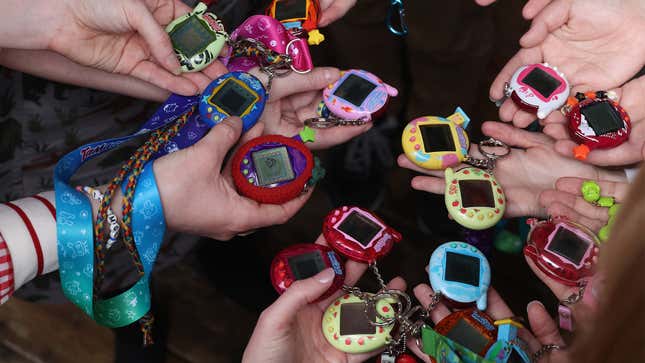 A handful of Tamagotchis are held out by people.