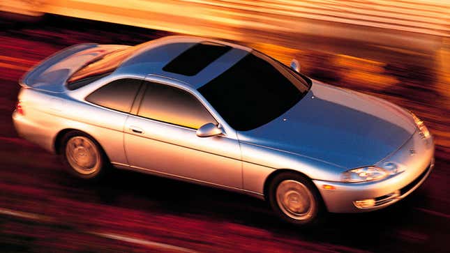 A photo of a silver Lexus coupe driving at sunset. 