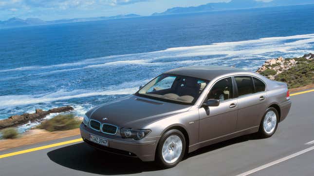 A photo of a BMW 7 Series sedan driving on an ocean road. 