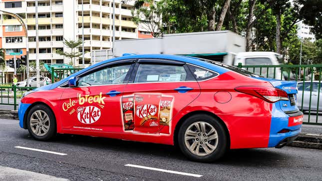A photo of a car wrapped with a red Kit Kat ad.