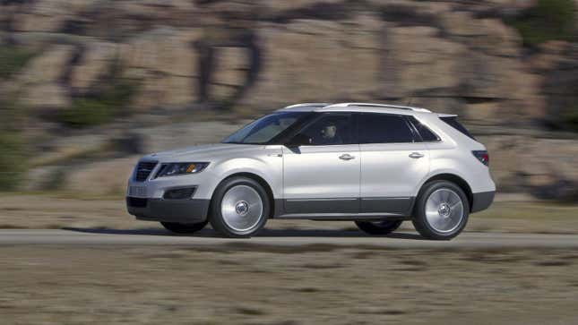 A silver 9-4X driving along a road in front of rocks