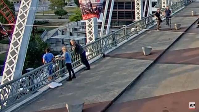 A screenshot showing Jon Bon Jovi and a production assistant talking to a woman on a bridge. 