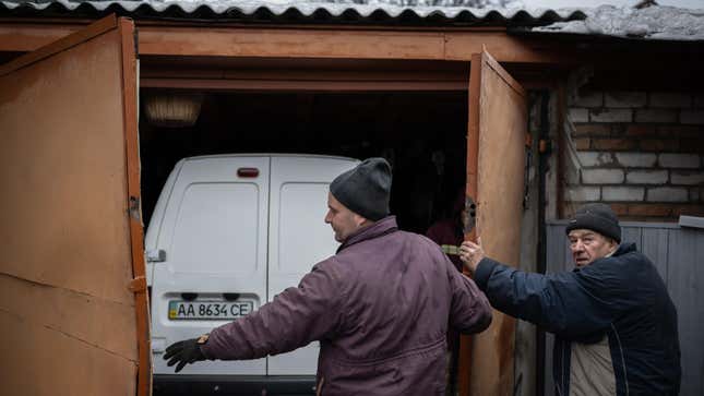 People try to secure their car as Russia stages another rocket attack on Ukraine’s capital, Kyiv, on December 11, 2023. 