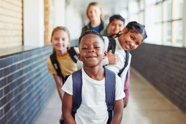 Portrait of a group of young children standing in a line in the hallway of a school