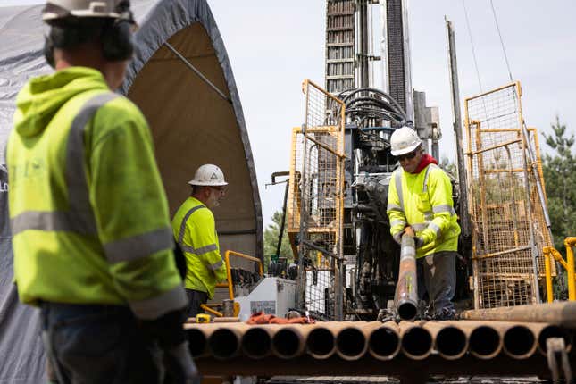 FILE - Driller Helper Chris Palmer, right, attaches a core sampling tube to a drilling rig at the Talon Metals Corporation drilling site, June 7, 2023, near Tamarack, Minn. Developers of a proposed nickel ore processing plant in western North Dakota that would supply electric automaker Tesla have reached a deal with the U.S. Department of Energy Department on spending nearly $115 million that the federal agency awarded the project last year. (Ben Hovland/Minnesota Public Radio via AP, File)