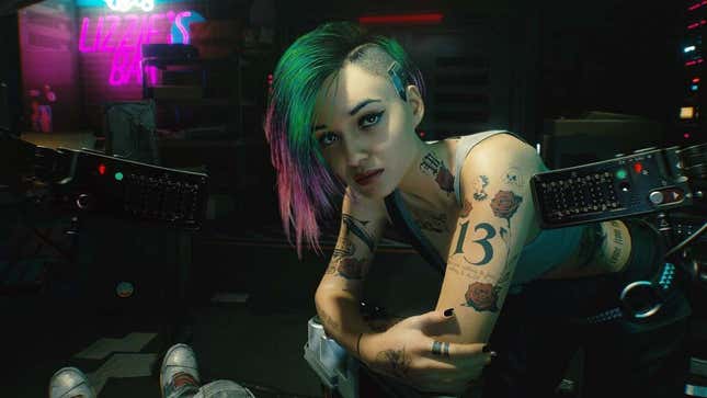 A screenshot of Cyberpunk 2077 shows a woman looking at the camera. 