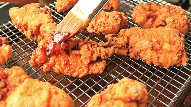 Brush basting fried chicken with hot sauce.