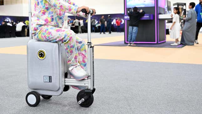 A girl rides a smart electric suitcase during a tech expo in Hawalli Governorate, Kuwait, Dec. 23, 2023.