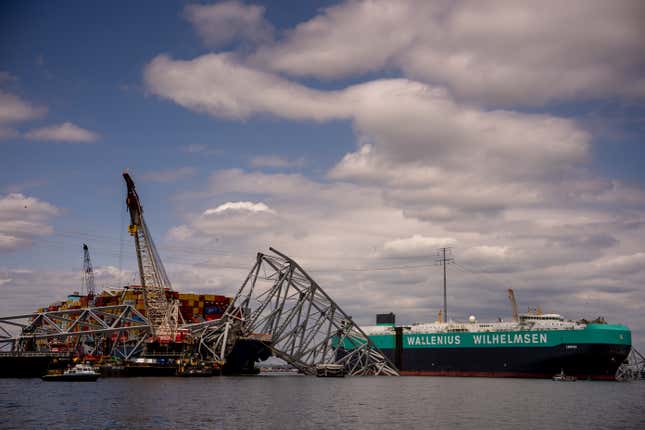 The "Carmen," the third and largest ship to leave port (R), sails past the cargo ship Dali (L) and the collapsed Francis Scott Key Bridge on April 25, 2024 in Baltimore, Maryland. Four weeks since the maritime accident in the Patapsco River, a temporary channel opens today to allow ships stuck in the Port of Baltimore to leave