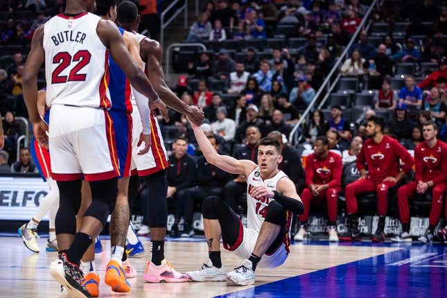 Mar 19, 2023; Detroit, Michigan, USA; Miami Heat guard Tyler Herro (14) is helped to his feet by center Bam Adebayo (13) in the first quarter against the Detroit Pistons at Little Caesars Arena.