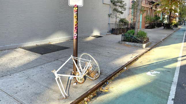  white bicycle, or ghost bike, with a sign saying rest in peace locked to a pole on a New York City street is a memorial at the site where a cyclist was killed by a crash motor vehicle. 
