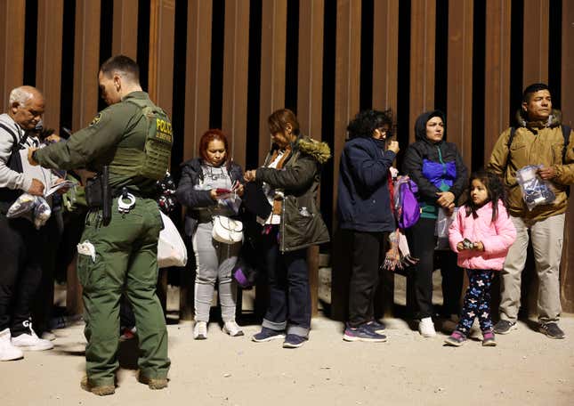 Immigrants seeking asylum in the United States stand in line as they are processed by U.S. Border Patrol agents in the early morning hours after crossing into Arizona from Mexico