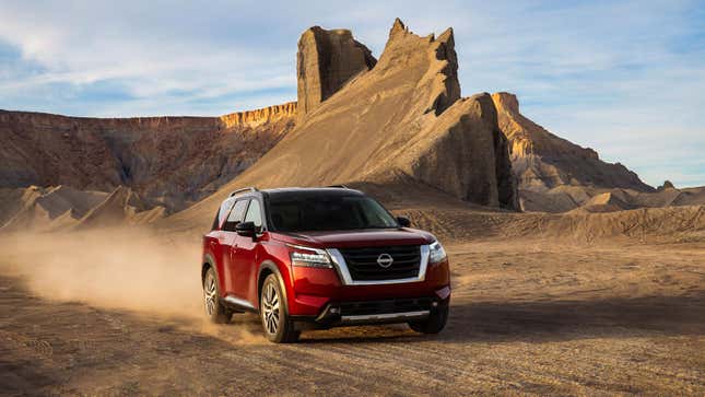 A red Nissan Pathfinder SUV driving on sand. 