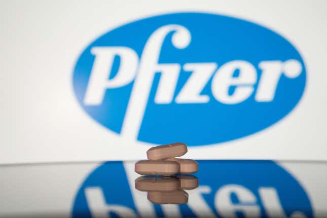 En esta ilustración fotográfica, se muestra una pila de píldoras en una pantalla con el logotipo de Pfizer en el fondo.