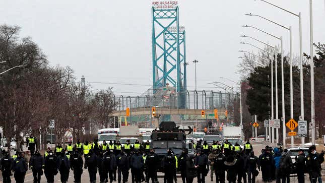 Police gather to clear protestors against COVID-19 vaccine mandates who blocked the entrance to the Ambassador Bridge in Windsor, Ontario, Canada, on February 13, 2022. - Canadian police resumed operations Sunday to clear a key U.S. border bridge occupied by trucker-led demonstrators angry over COVID-19 restrictions, as authorities began making arrests in their bid to quell a movement that has also paralyzed downtown Ottawa.