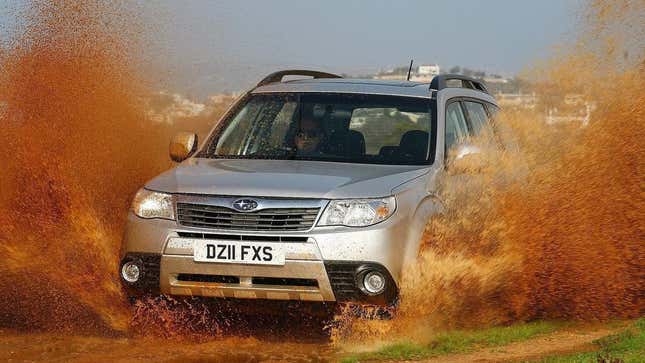 A Subaru Forester making a giant splash as it drives through a mud puddle
