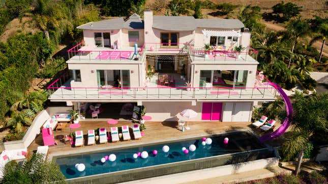 An exterior view of Barbie's pink Malibu Dream House is shown. It features a massive pink water slide.