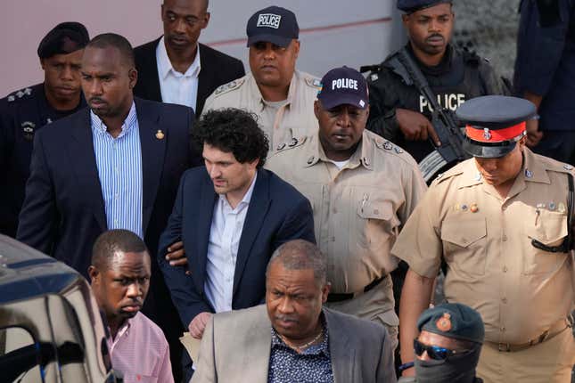 FILE - FTX founder Sam Bankman-Fried, center left, is escorted out of Magistrate Court following a hearing in Nassau, Bahamas, Dec. 19, 2022. Bankman-Fried, charged with a host of financial crimes, was arrested in the Bahamas on Dec. 12, 2022. (AP Photo/Rebecca Blackwell, File)