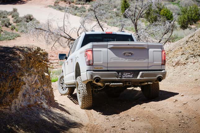 Rear 3/4 view of a grey 2024 Ford F-150 Tremor going down a hill