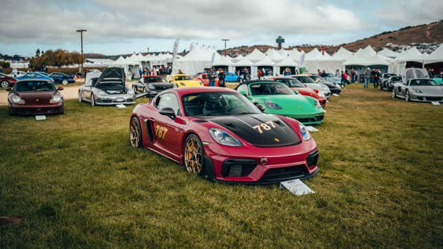 A red Porsche Cayman GT4 is parked on grass