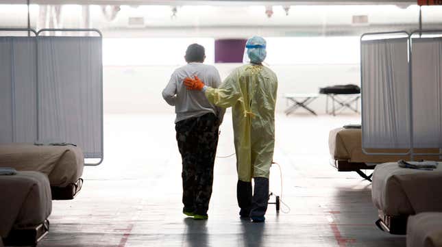 A nurse supports a patient as they walk in the covid-19 alternative care site, built into a parking garage, at Renown Regional Medical Center in Reno, Nevada, December 16, 2020.