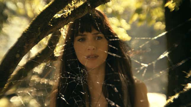 Dakota Johnson as Madame Web stands behind a spider web.