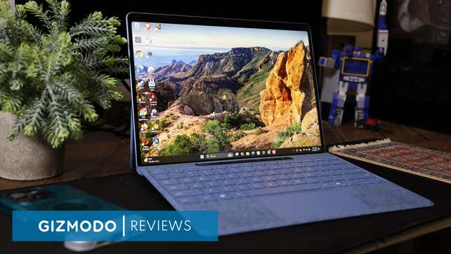 A Microsoft Surface Pro with the main desktop wallpaper surrounded by a desk plant and toy.