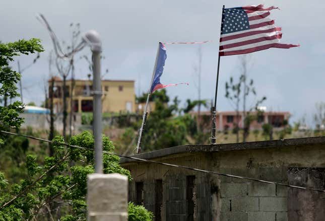 FILE - Deteriorated U.S. and Puerto Rico flags fly on a roof eight months after the passing of Hurricane Maria in the Barrio Jacana Piedra Blanca area of Yabucoa, a town where many continue without power in Puerto Rico, May 16, 2018. A federal judge on Tuesday, Nov. 14, 2023, tentatively approved a portion of the newest plan to restructure $10 billion of debt owed by Puerto Rico’s power company amid heated negotiations between creditors and the U.S. territory’s government. (AP Photo/Carlos Giusti, File)