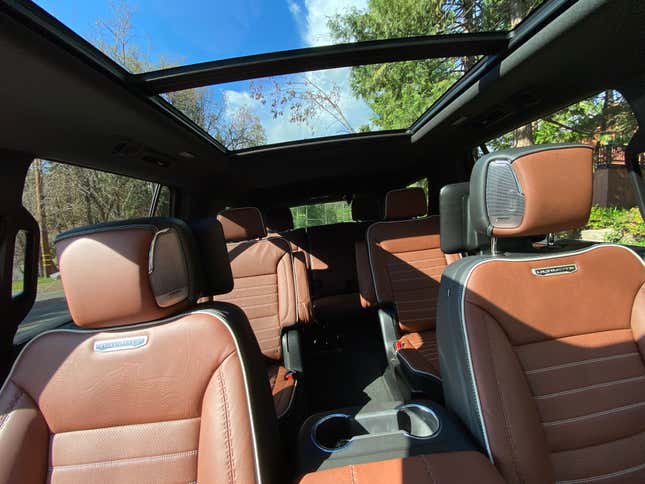 A photo looking into the cabin of the Yukon showing all three rows of brown leather seats and the giant panoramic sunroof