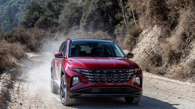 A red Hyundai Tucson driving on a dirt road