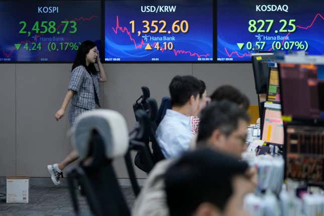 A currency trader passes by the screens showing the Korea Composite Stock Price Index (KOSPI), left, and the foreign exchange rate between U.S. dollar and South Korean won, center, at the foreign exchange dealing room of the KEB Hana Bank headquarters in Seoul, South Korea, Wednesday, Sept. 27, 2023. Shares in Asia were mostly lower on Wednesday after Wall Street’s ugly September got even worse, with benchmarks dropping back to where they were in June.(AP Photo/Ahn Young-joon)