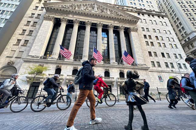 FILE - A man passes the &quot;Fearless Girl&quot; statue in front of the New York Stock Exchange in New York on Nov. 3, 2023. Black, white, Hispanic and Asian adults in the U.S. largely agree that the government should focus on the economy and foreign policy issues in 2024, but recent polling shows that views diverge on some high-profile topics, including racism and immigration. That&#39;s according to two recent polls by The Associated Press-NORC Center for Public Affairs Research and AAPI Data. (AP Photo/Ted Shaffrey, File)