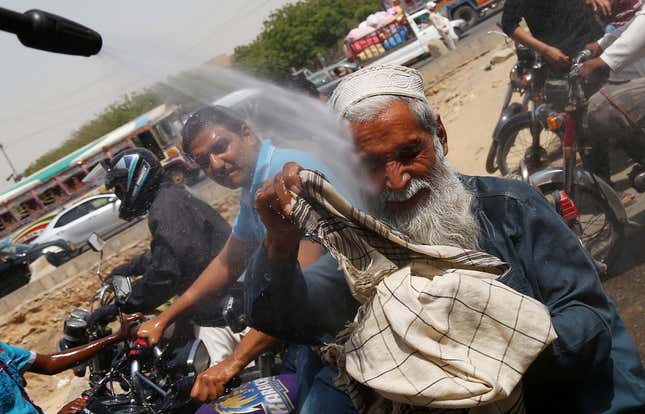A man sprays people with water on a road in Karachi on May 22.