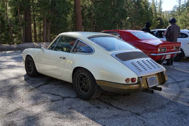 A white and gold hot rod Porsche 911 is parked next to a red Camaro.