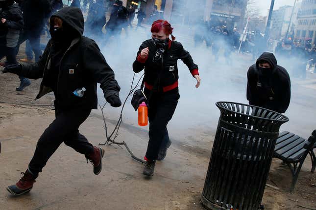 Activists run after being hit by a stun grenade while protesting against U.S. President Donald Trump on the sidelines of the inauguration.