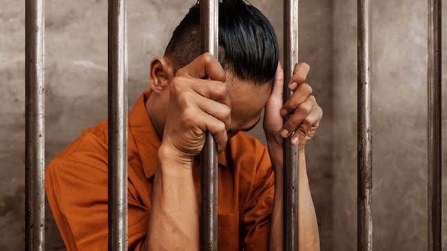 The photo shows a man behind bars with his head bowed.