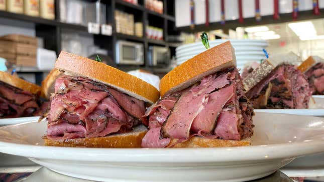 A photo of a pastrami sandwich on a plate in a deli. 